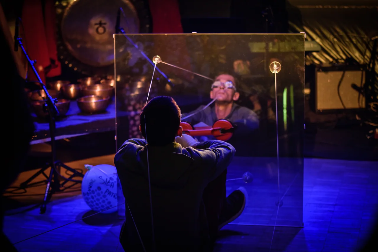 Artysta na pierwszym planie, z twarzą odbitą w lustrze, podczas performansu Woda – Pragnienie w Grodnie.